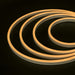 An image of the NimbusFlex® CCT Adjustable LED Rope Light in a warm white spiral pattern from above on a flat black surface entering from right frame.