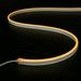 An image of the NimbusFlex® CCT Adjustable LED Rope Light in a warm white S-shaped pattern from above on a flat black surface covered in water droplets.